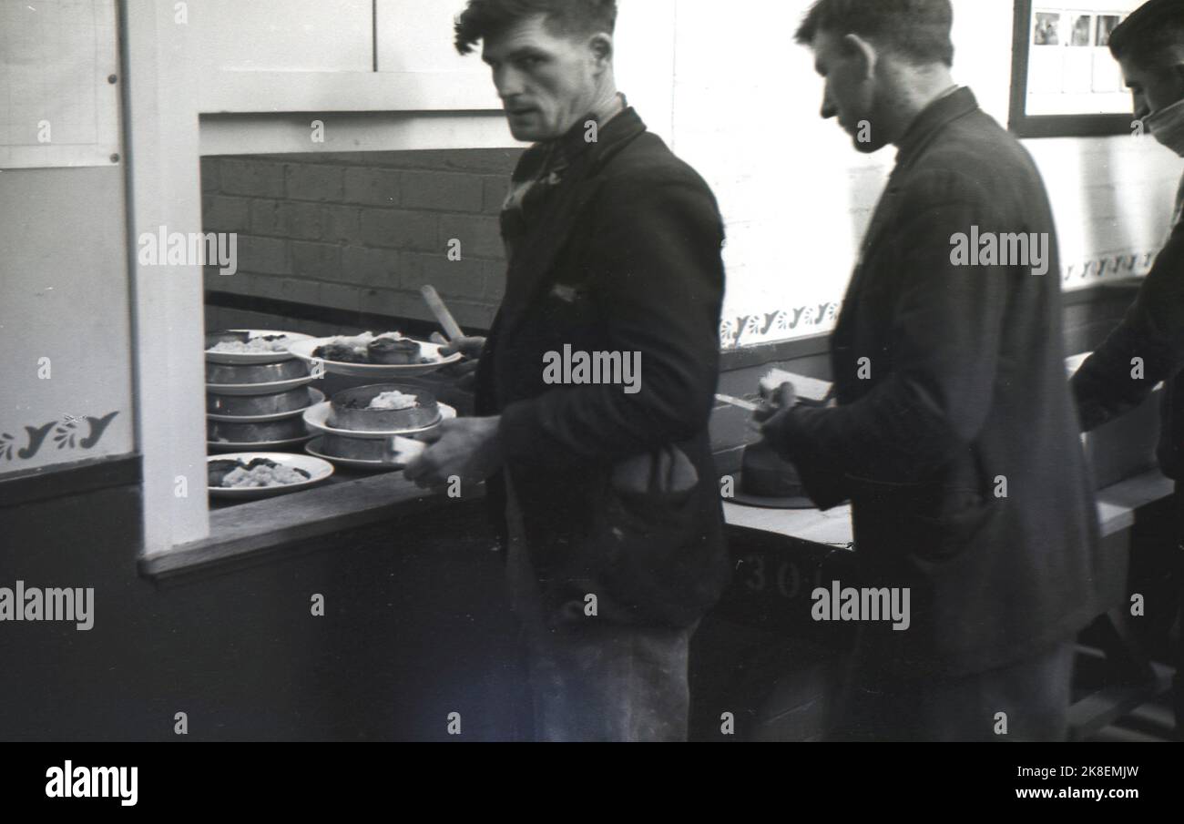1938, historical, former mine workers at the Ministry of Labour training centre at the newly establised Treforest industrial estate, collecting their lunchtime meal of pie & mash from the kitchen serving hatch of the canteen, South Wales, UK. Stock Photo