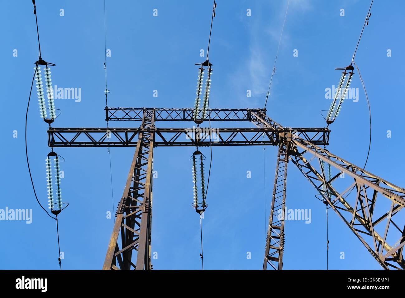 High voltage power pylons against blue sky and sun rays Stock Photo - Alamy