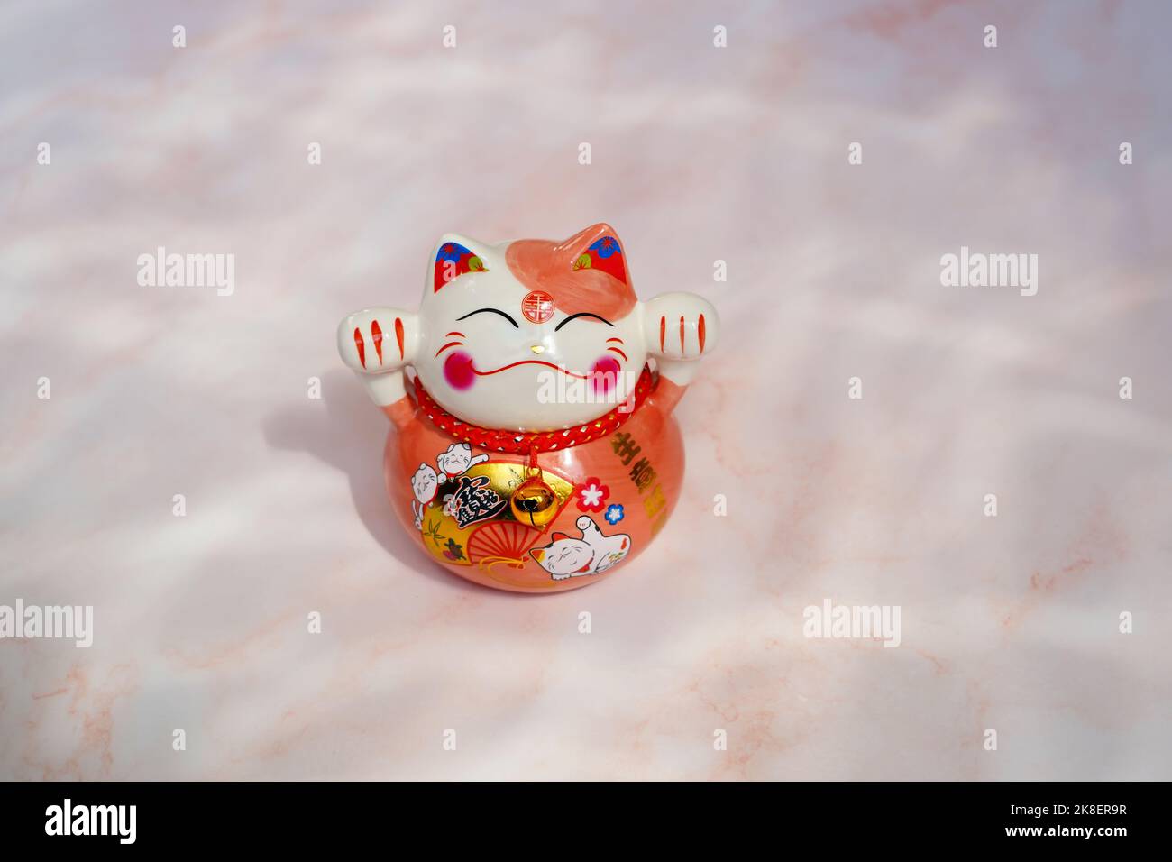 Japanese beckoning cat (maneki neko) made of porcelain. A maneki neko is a traditional symbol of good luck and fortune. Stock Photo