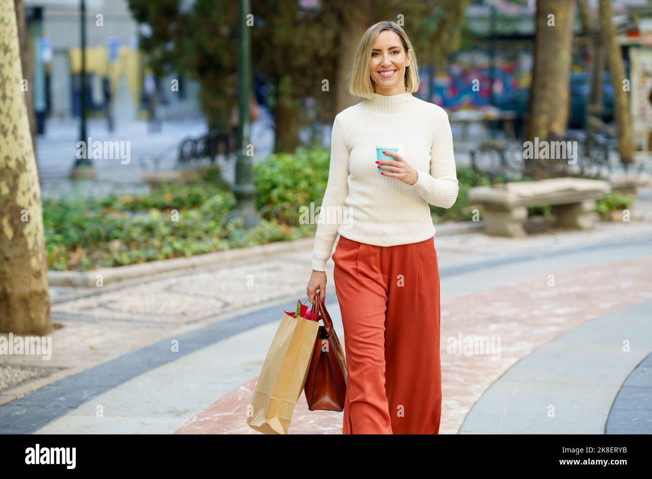 Smiling woman with shopping bags and takeaway drink Stock Photo