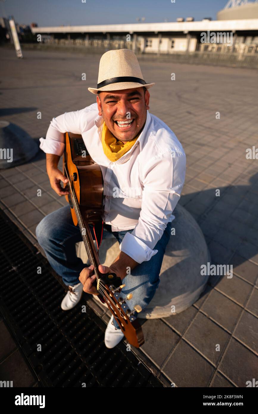 Happy guitarist wearing hat playing guitar on sunny day Stock Photo Alamy