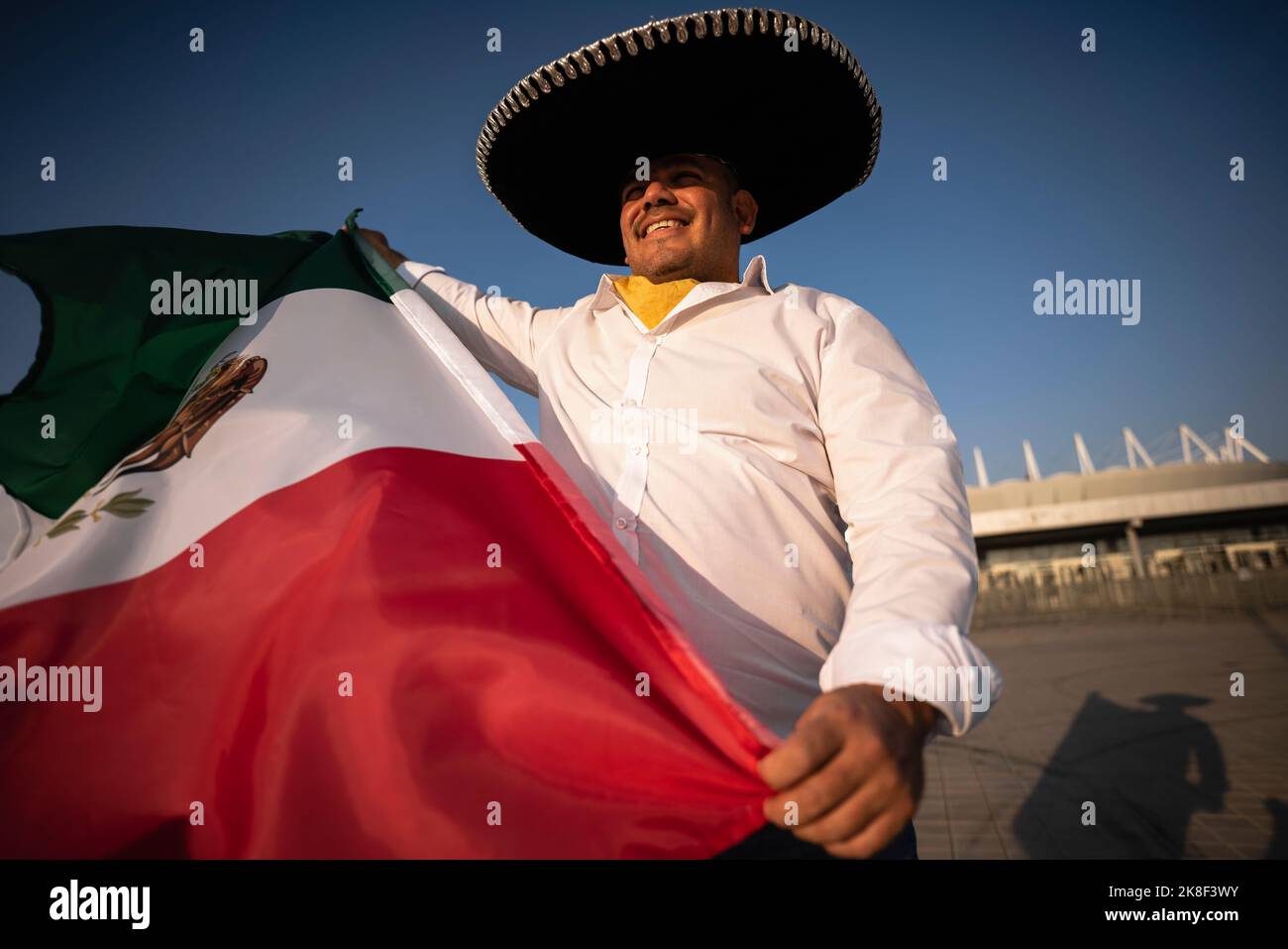 Smiling man wearing sombrero holding Mexican flag on sunny day Stock Photo