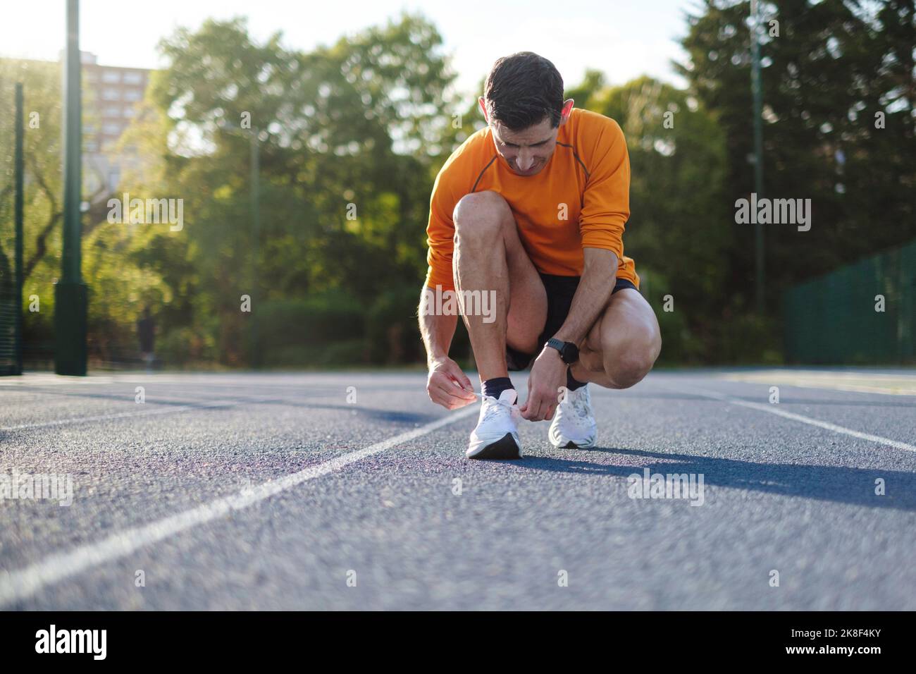 Sportsman tying shoe laces on track Stock Photo - Alamy