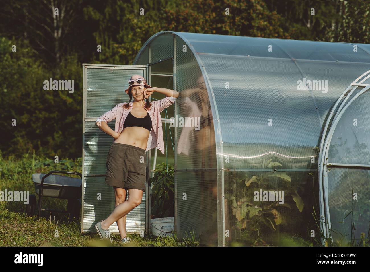 Smiling farmer standing with legs crossed at knee by greenhouse Stock Photo