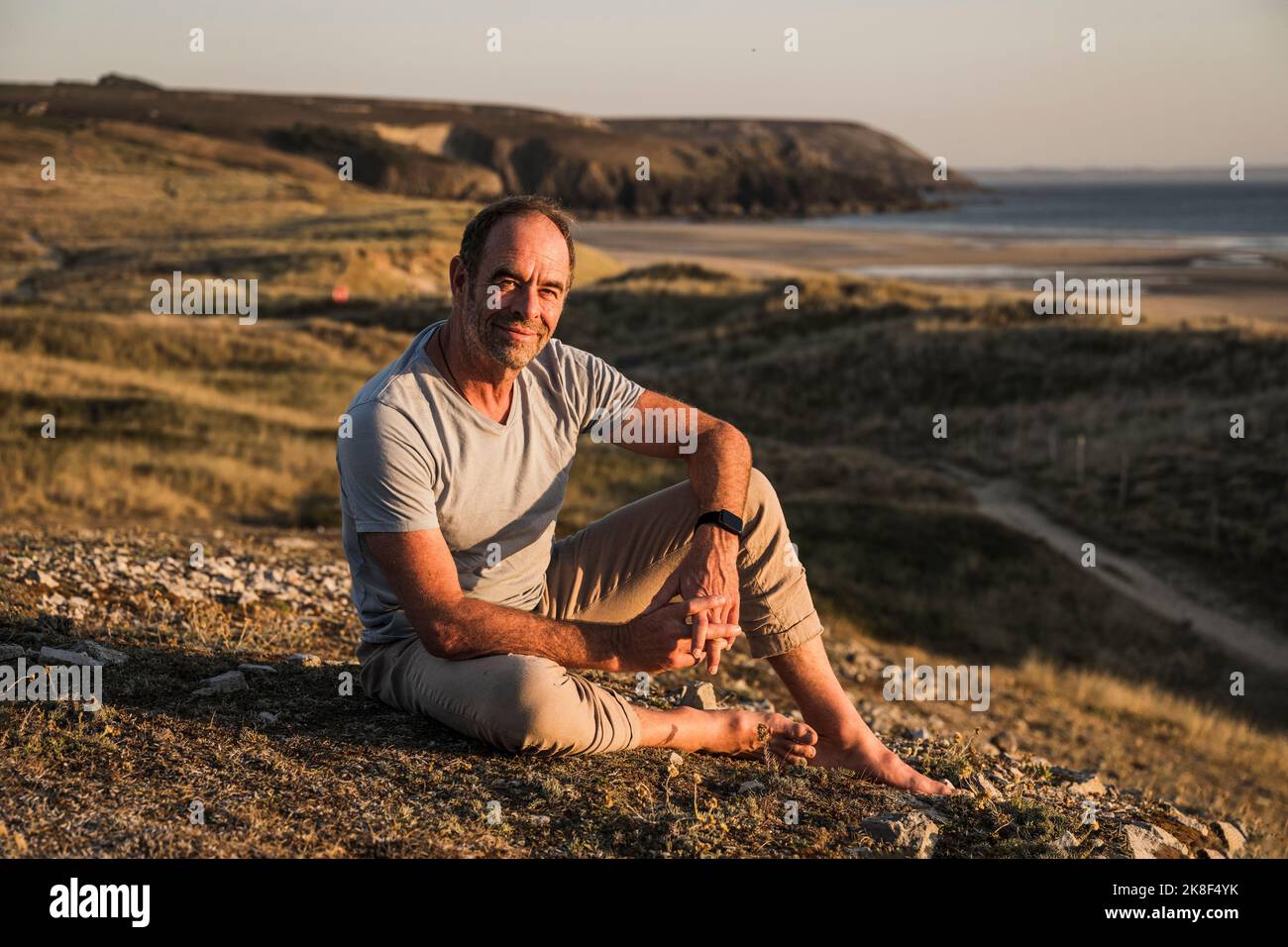Contemplative mature man sitting on hill Stock Photo