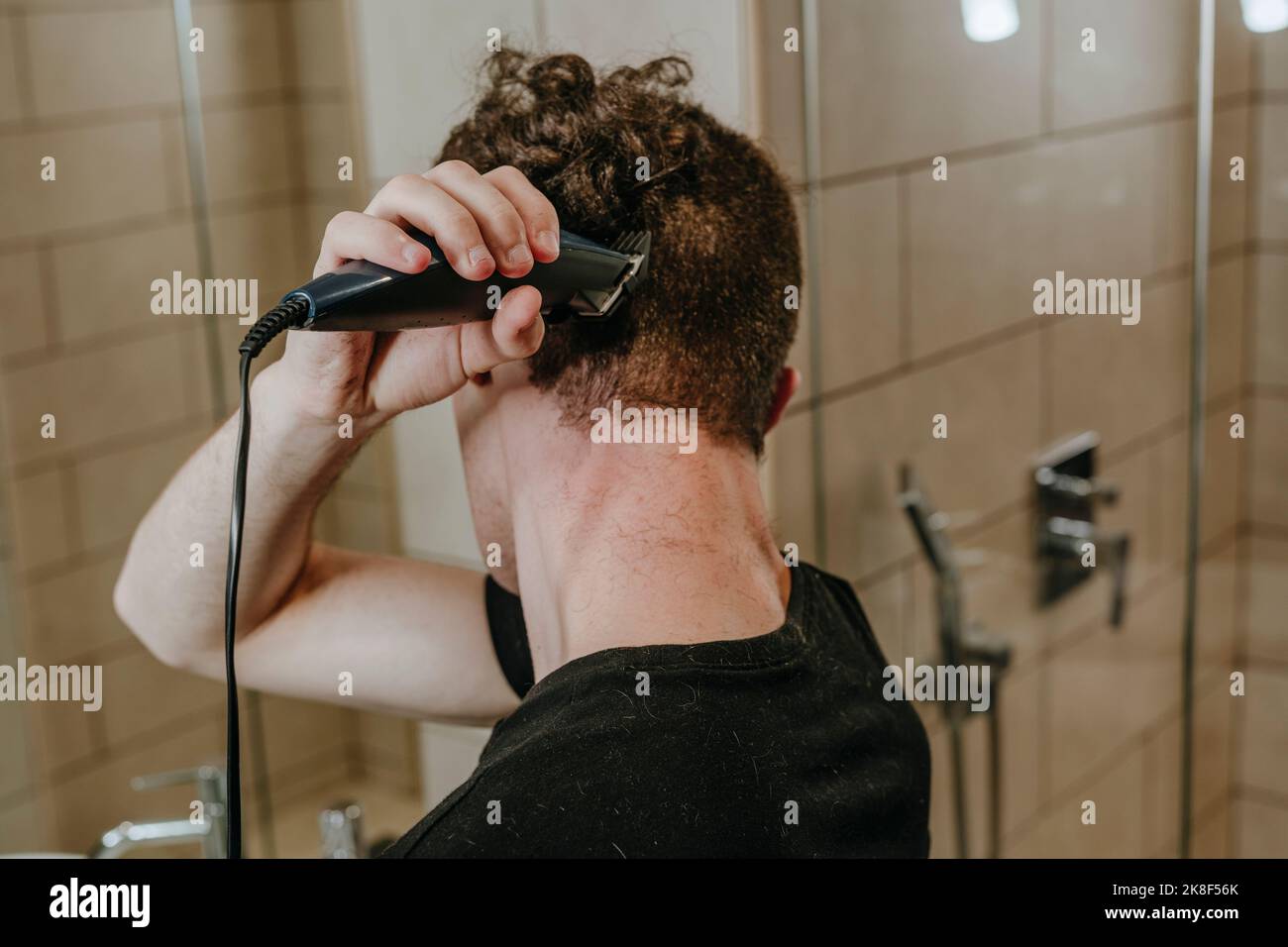 Young man shaving own hair in bathroom at home Stock Photo