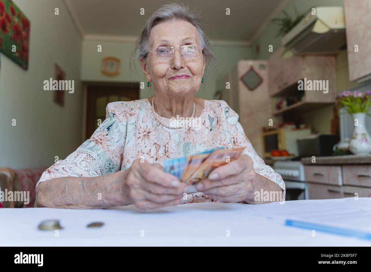 Smiling senior woman with paper currency at home Stock Photo