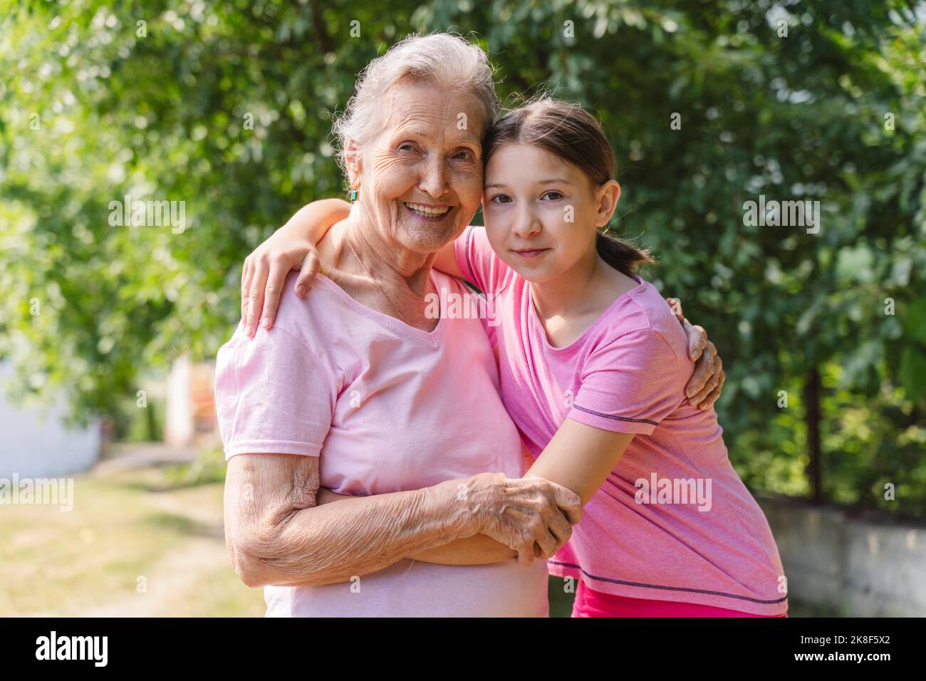 Happy senior woman hugging granddaughter standing in park Stock Photo