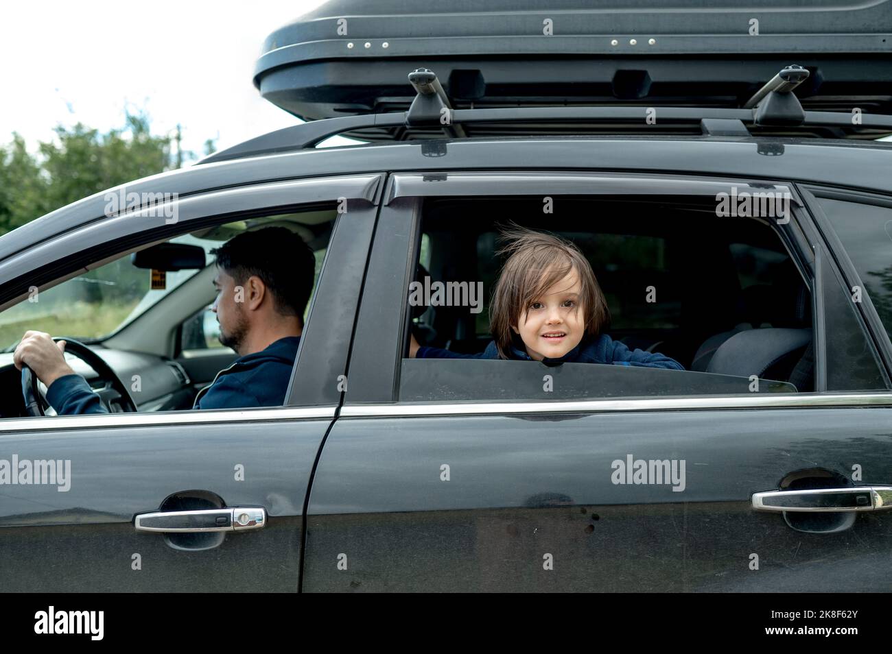 Cute boy looking out of window with father driving car Stock Photo - Alamy