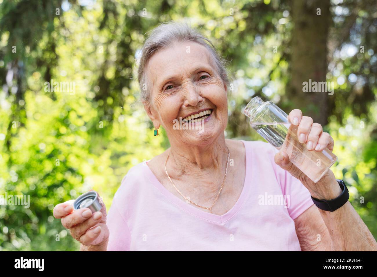 Happy senior woman holding water bottle at park Stock Photo - Alamy