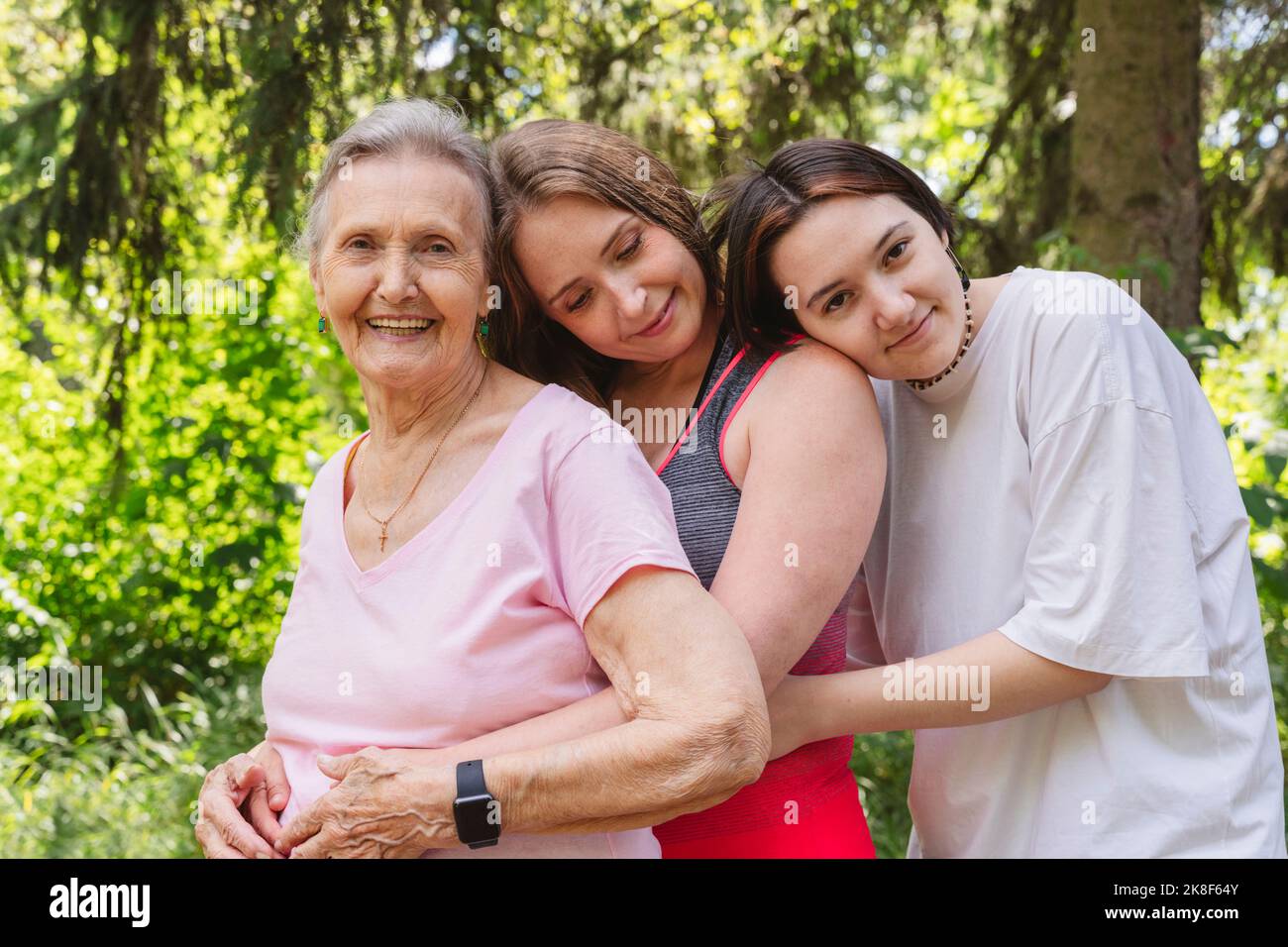 Smiling senior woman with daughter and granddaughter hugging each other at park Stock Photo
