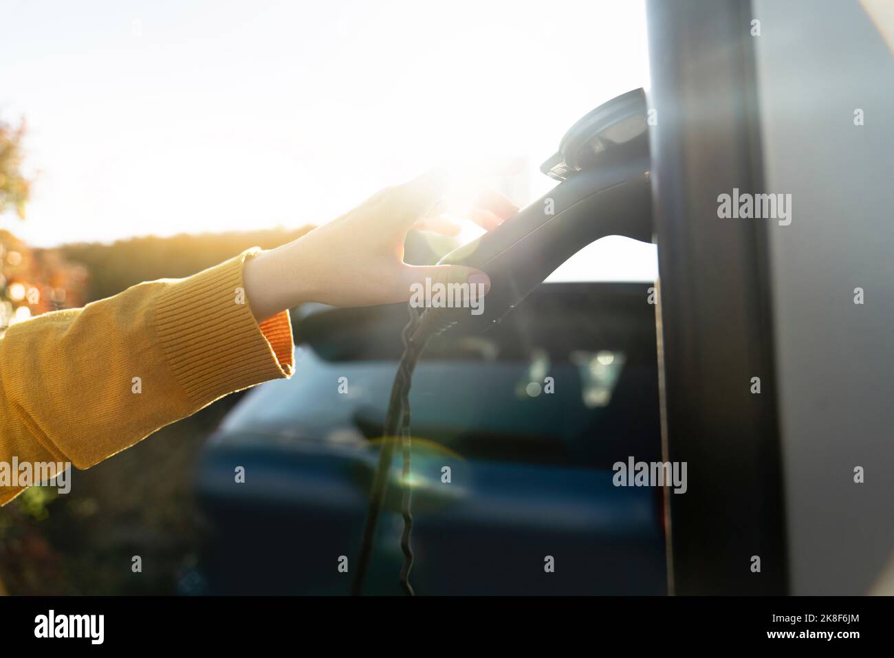Hand of woman touching electric plug at vehicle charging station Stock