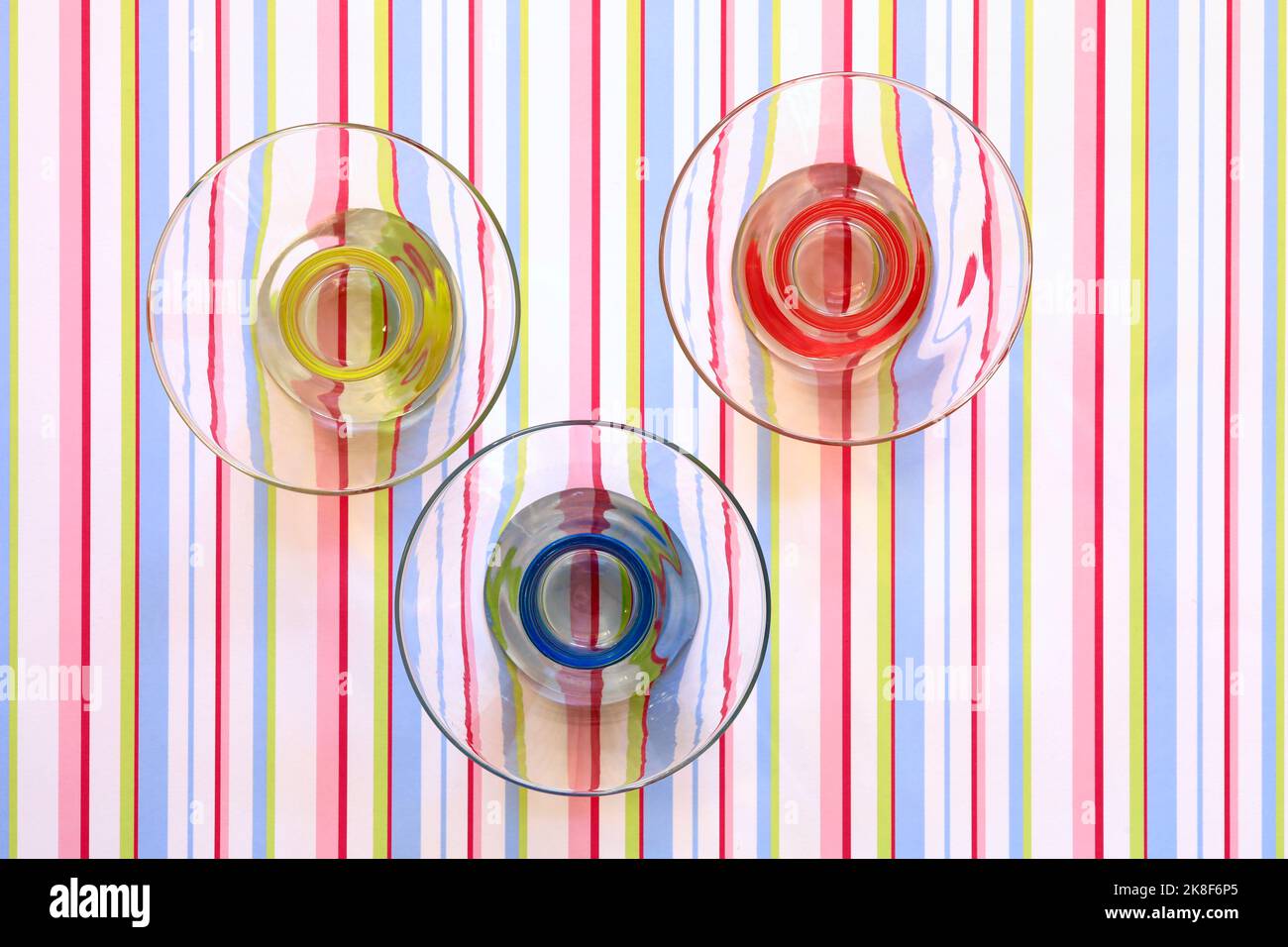 Red, yellow and blue bowls on a striped pattern Stock Photo