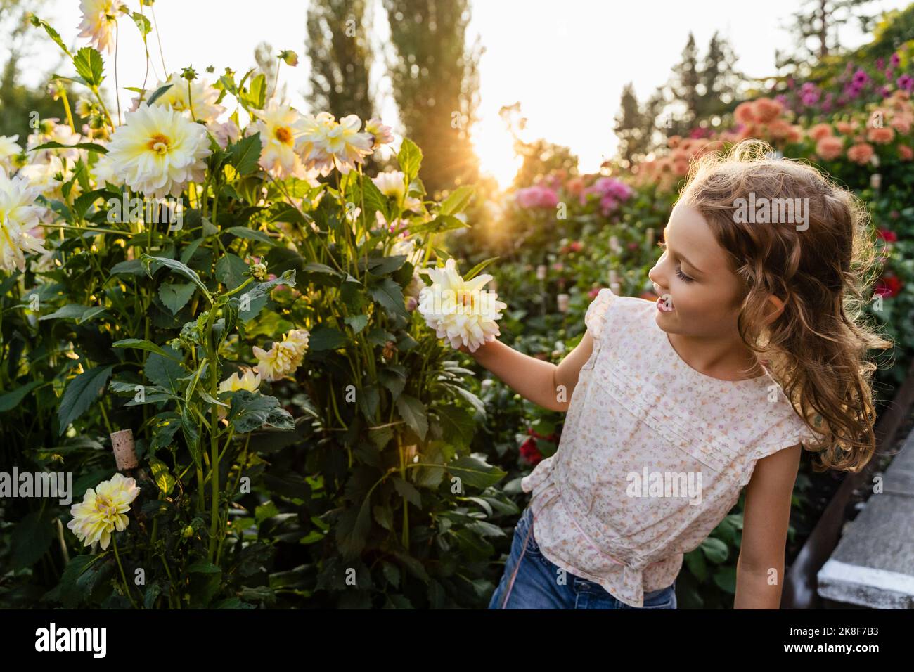 Little girl smelling flowers in garden Stock Photo