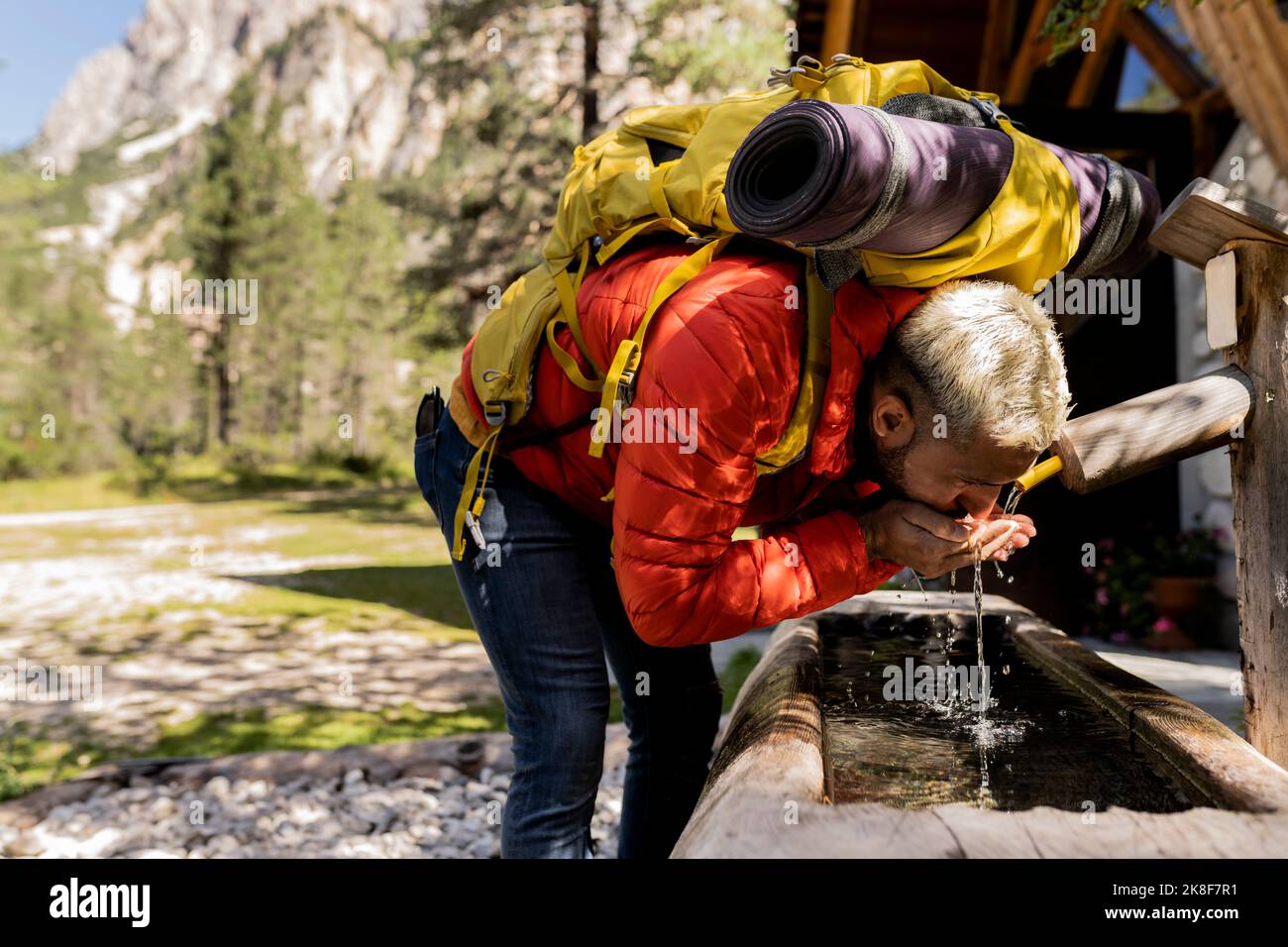Hiker with backpack drinking water from fountain Stock Photo
