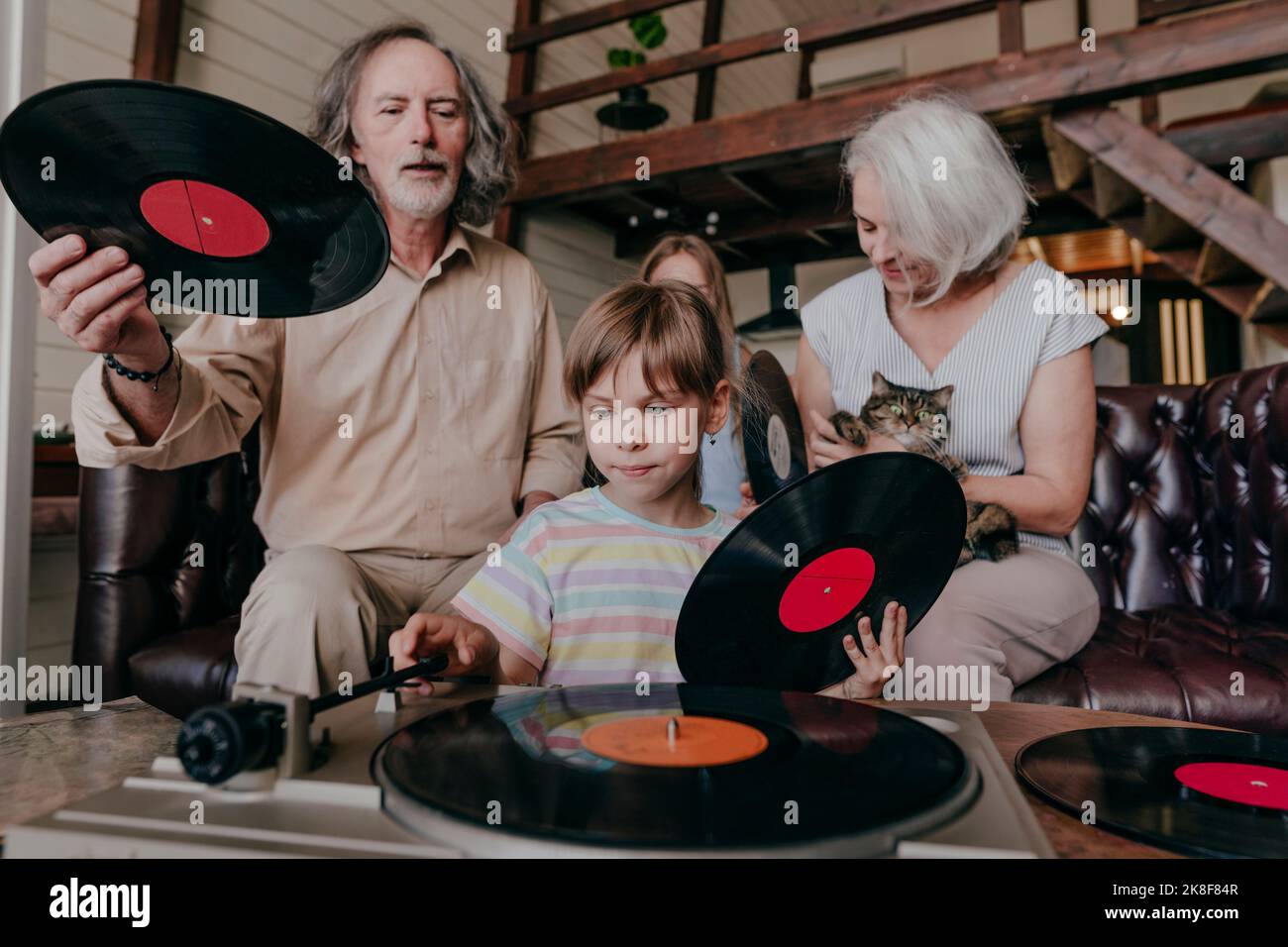 Granddaughter changing record on turntable with grandparents at home