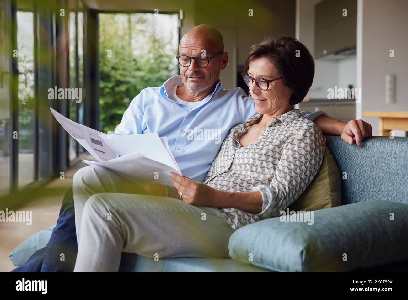 Smiling man with woman reading documents at home Stock Photo