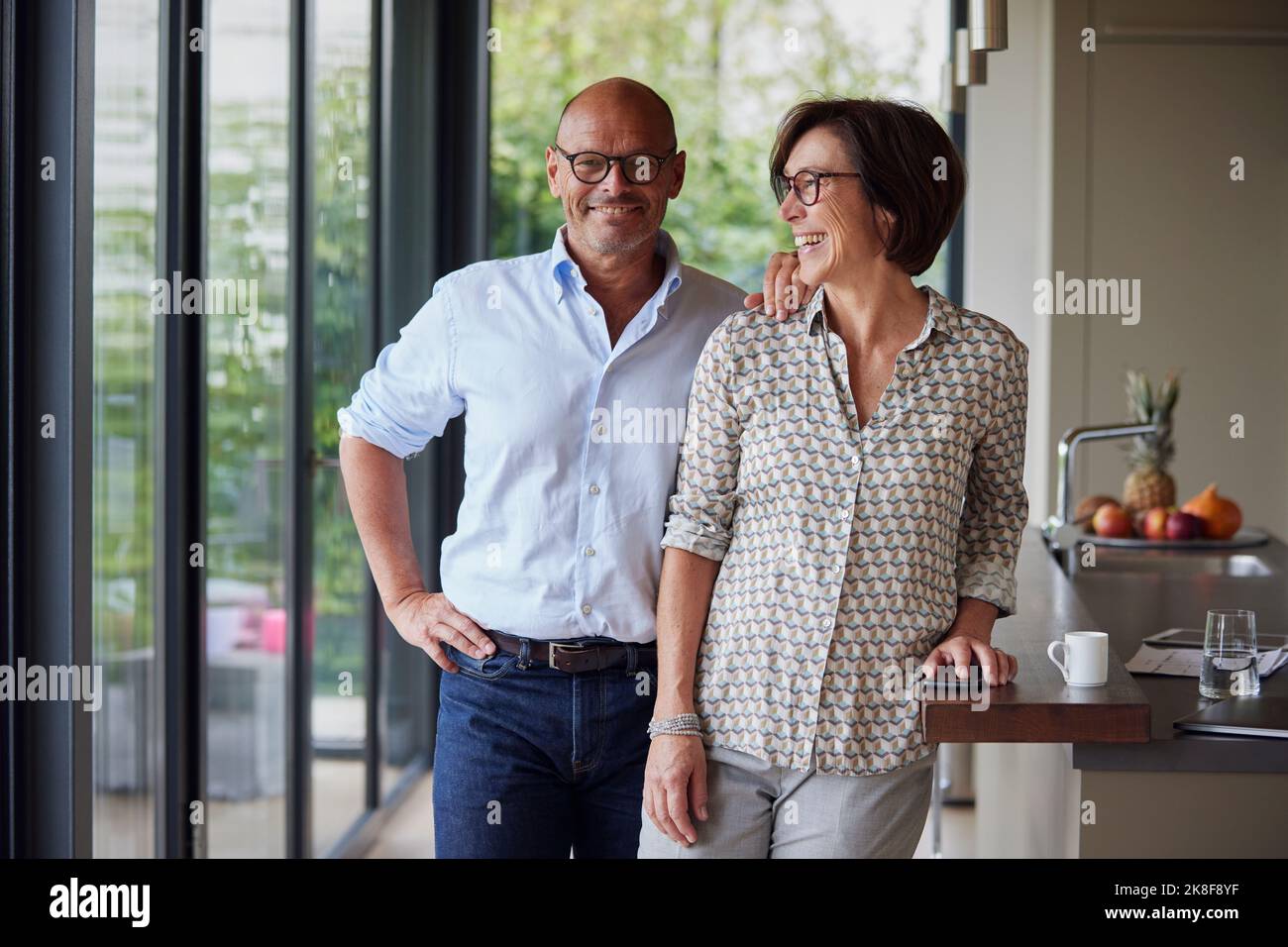 Cheerful woman with man standing by kitchen island Stock Photo
