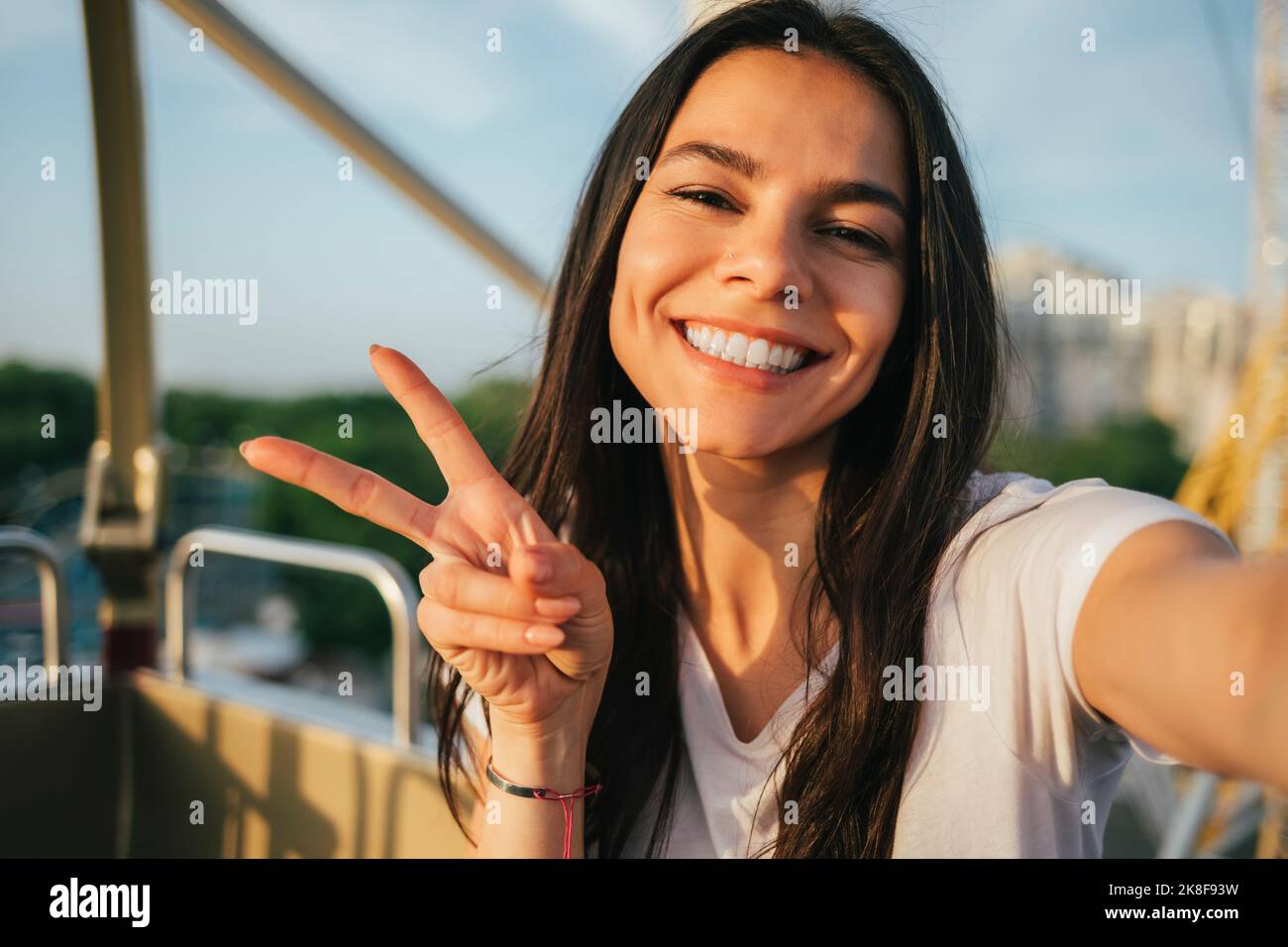 Happy woman showing peace gesture and taking selfie in Ferris wheel Stock Photo