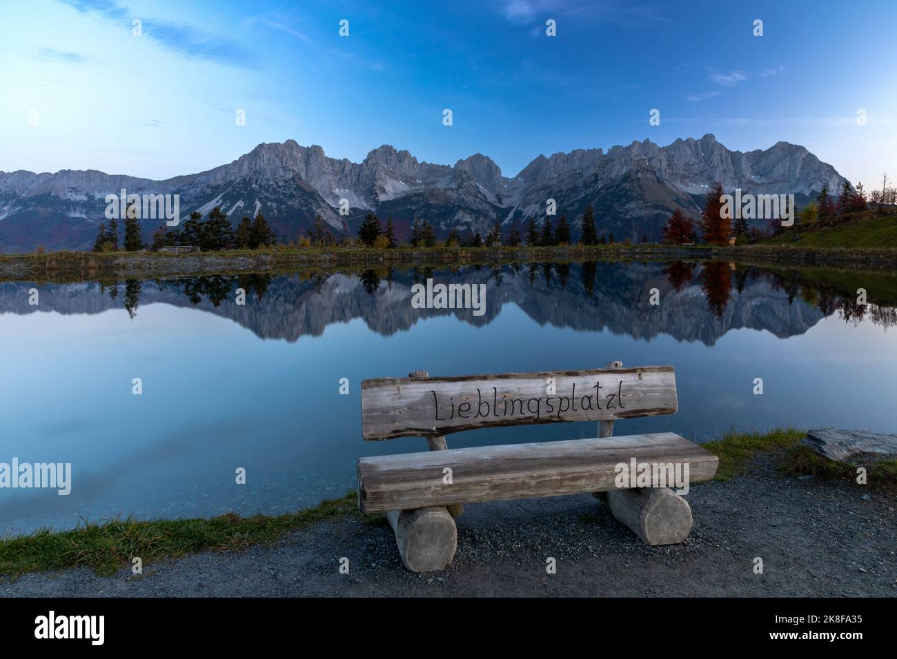 Lieblingsplatzl, favorite place, bench at lake Astbergsee with Wilder Kaiser mountains reflected, Going, Tyrol, Austria Stock Photo