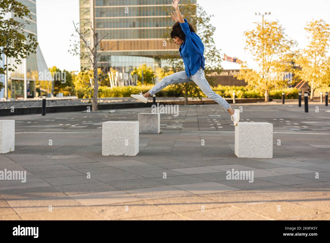 Carefree woman with arms raised jumping on concrete block Stock Photo