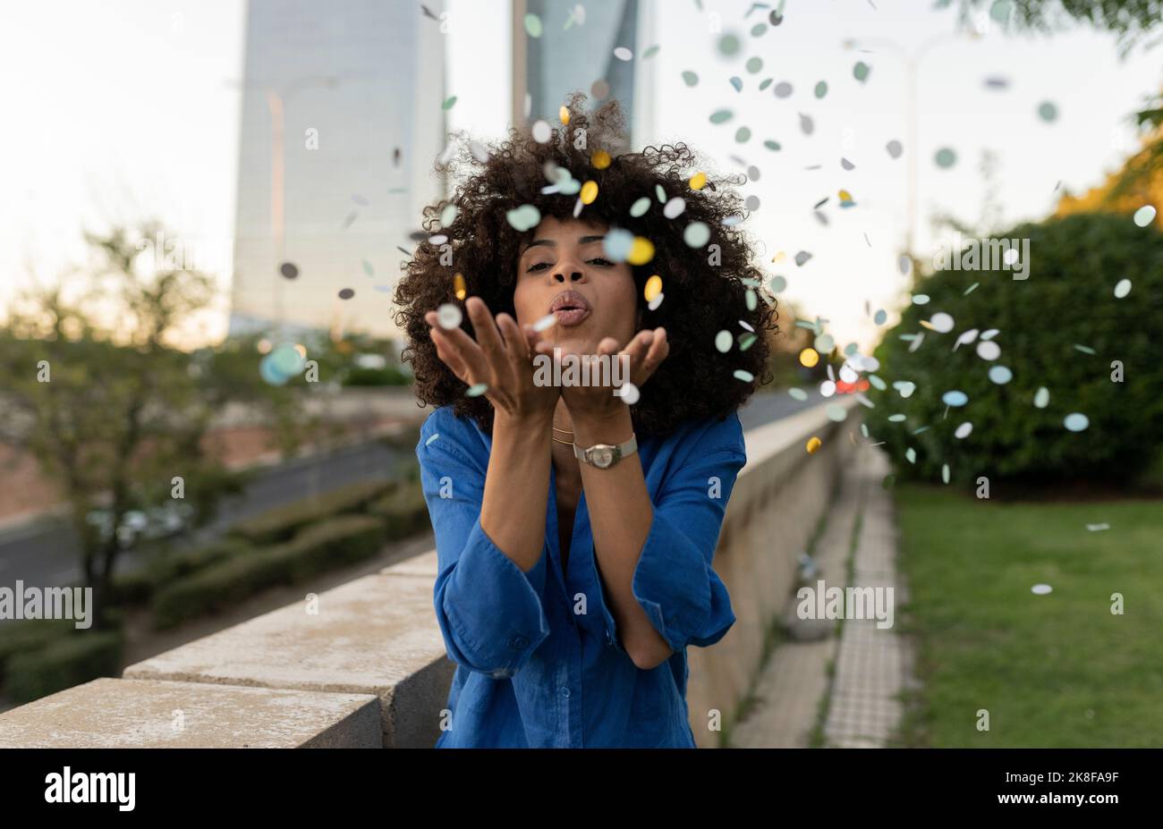 Woman blowing confetti standing by wall Stock Photo Alamy