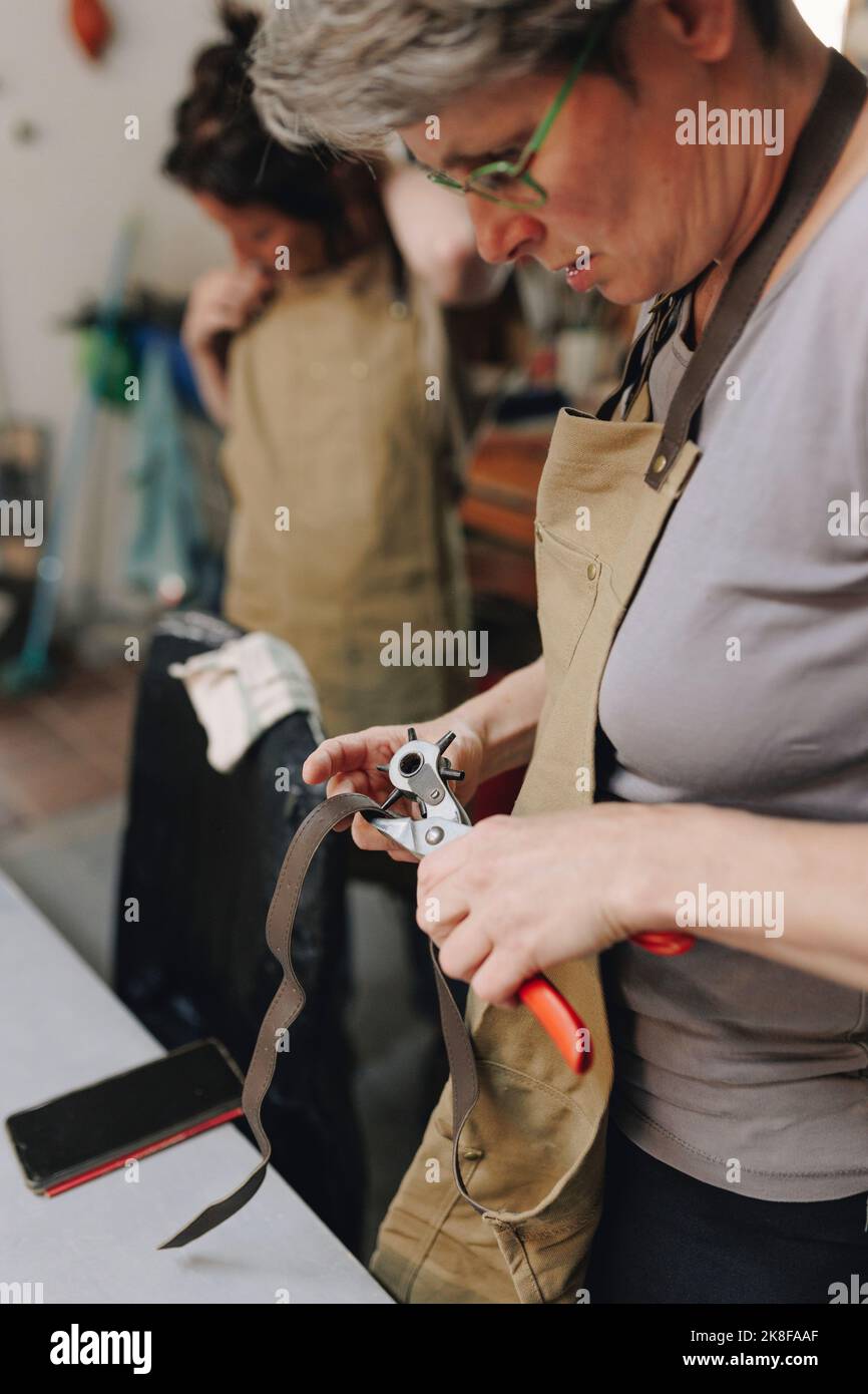 Entrepreneur making hole with equipment on leather belt Stock Photo Alamy