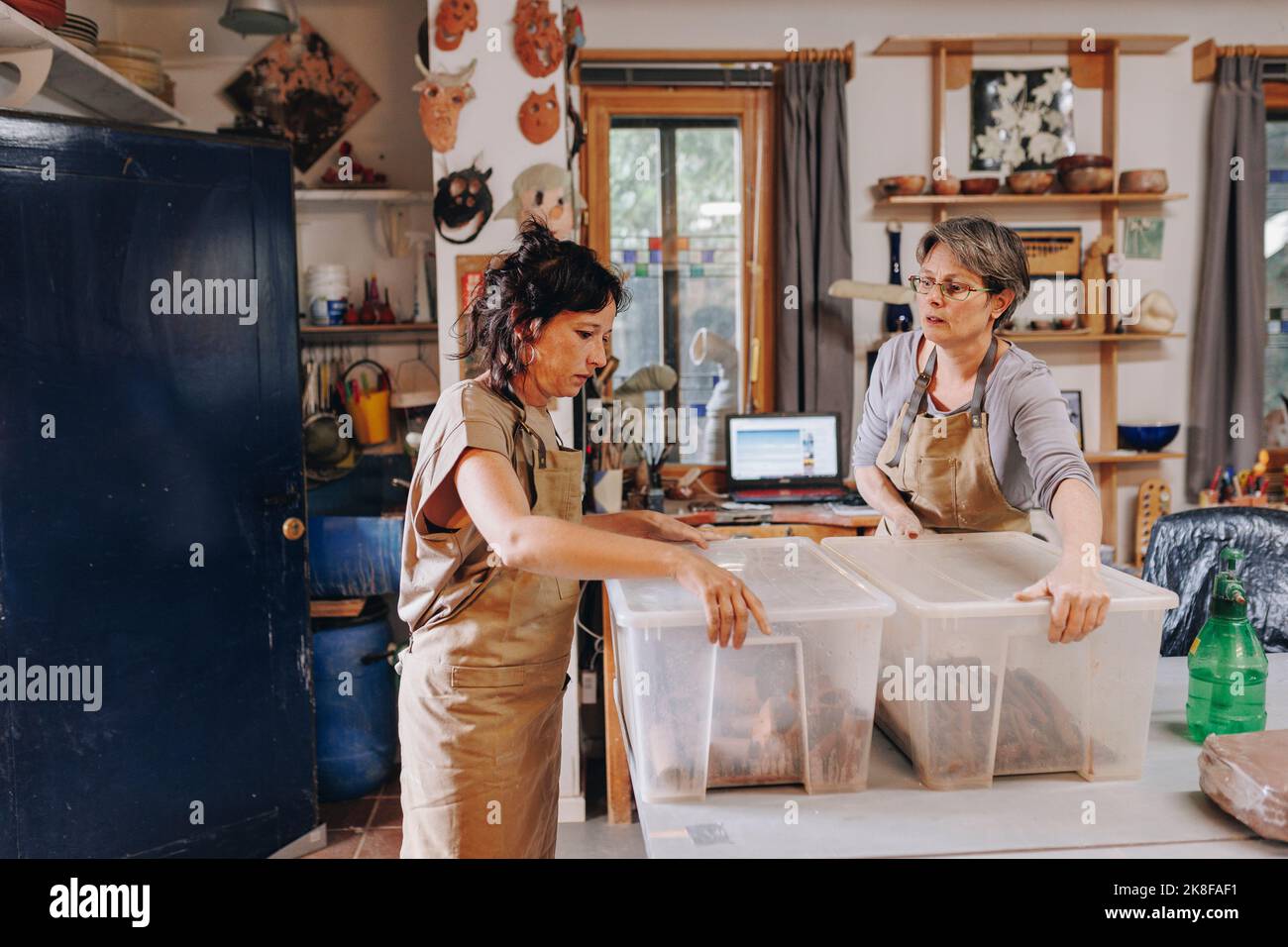 Entrepreneur with colleague holding plastic containers at ceramics workshop Stock Photo