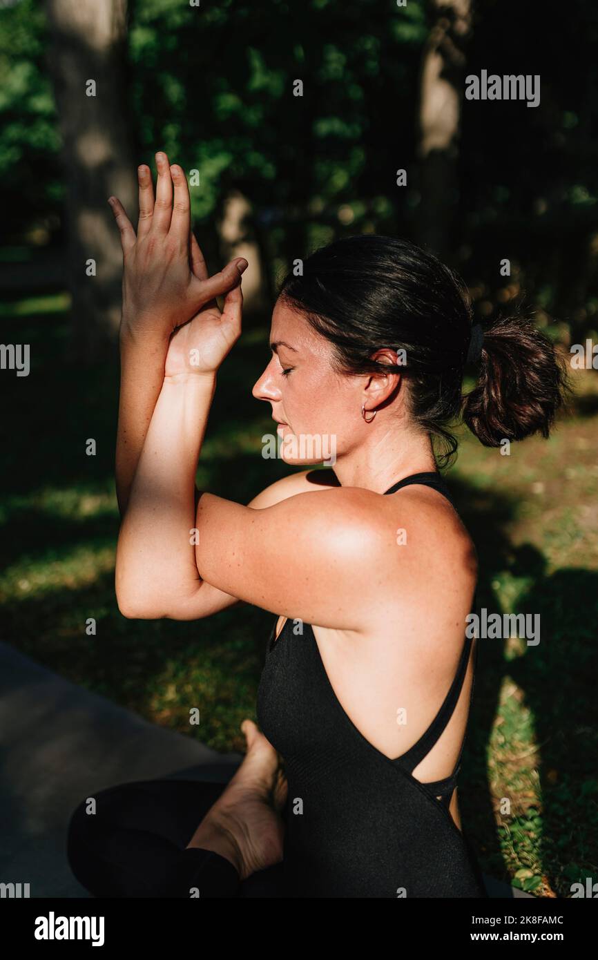 Yoga teacher with eyes closed exercising vajrasana garudasana posture in park Stock Photo
