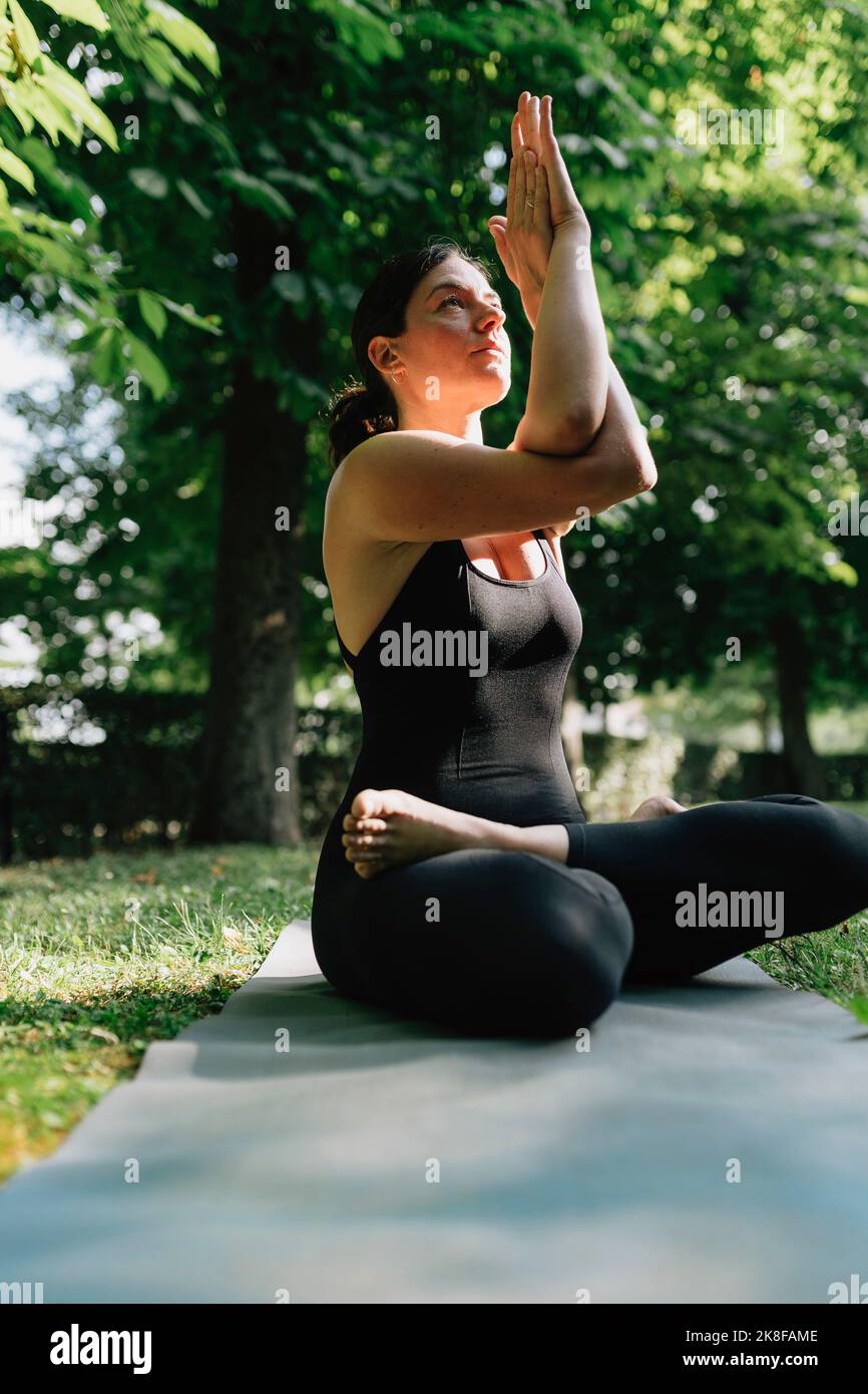 Yoga teacher exercising vajrasana garudasana posture in park Stock Photo