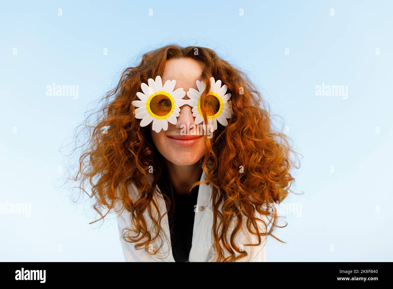 Smiling woman with curly hair wearing sunflower sunglasses Stock Photo