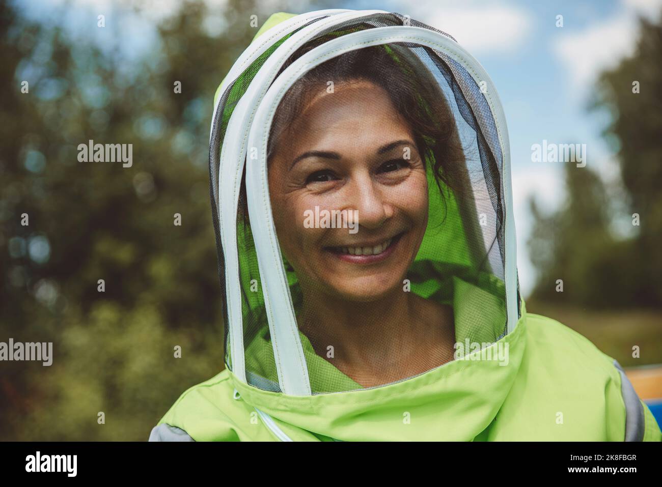 Happy beekeeper wearing protective suit at apiary Stock Photo