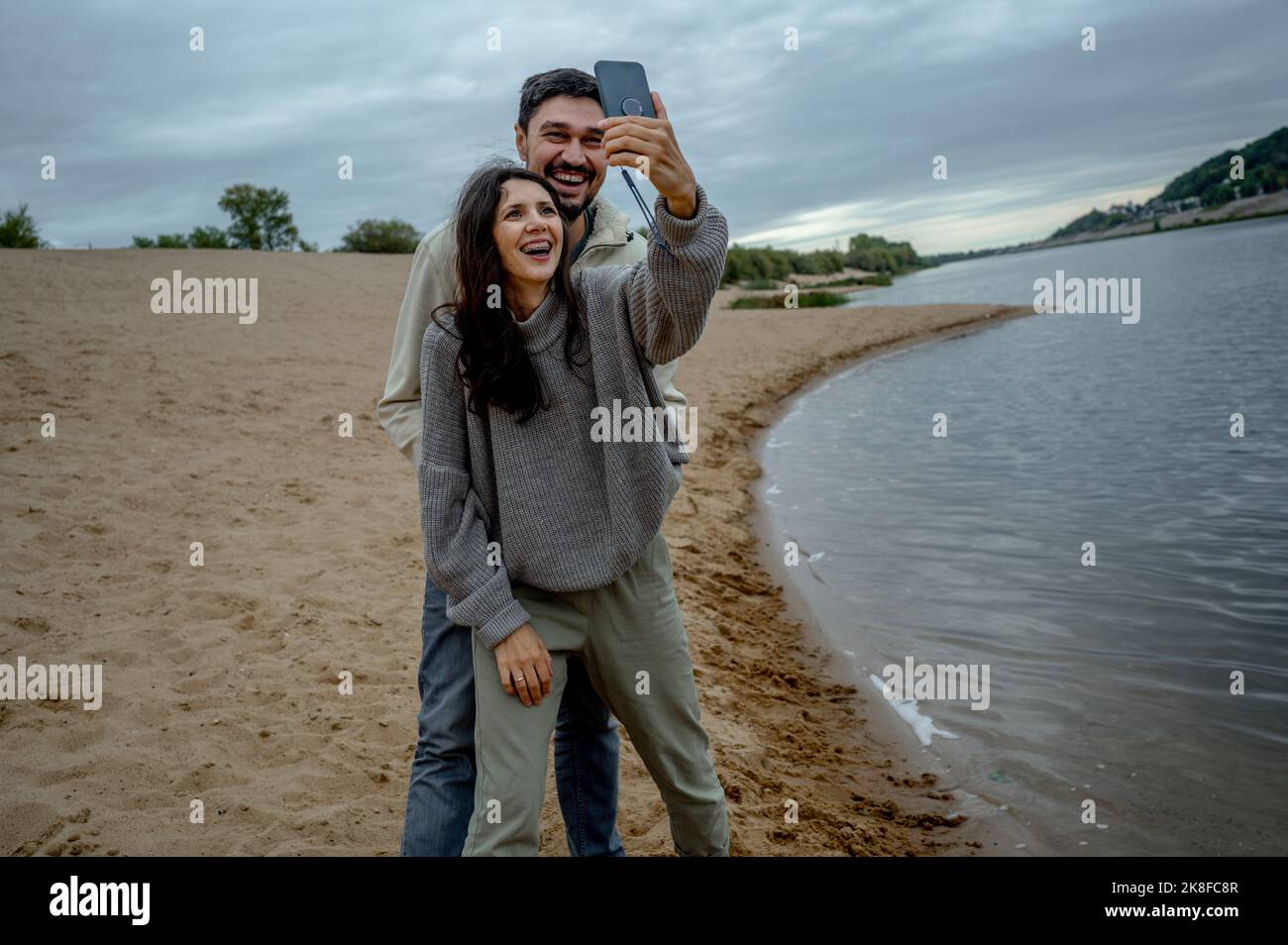 Happy couple having fun taking selfie through smart phone by river Stock Photo