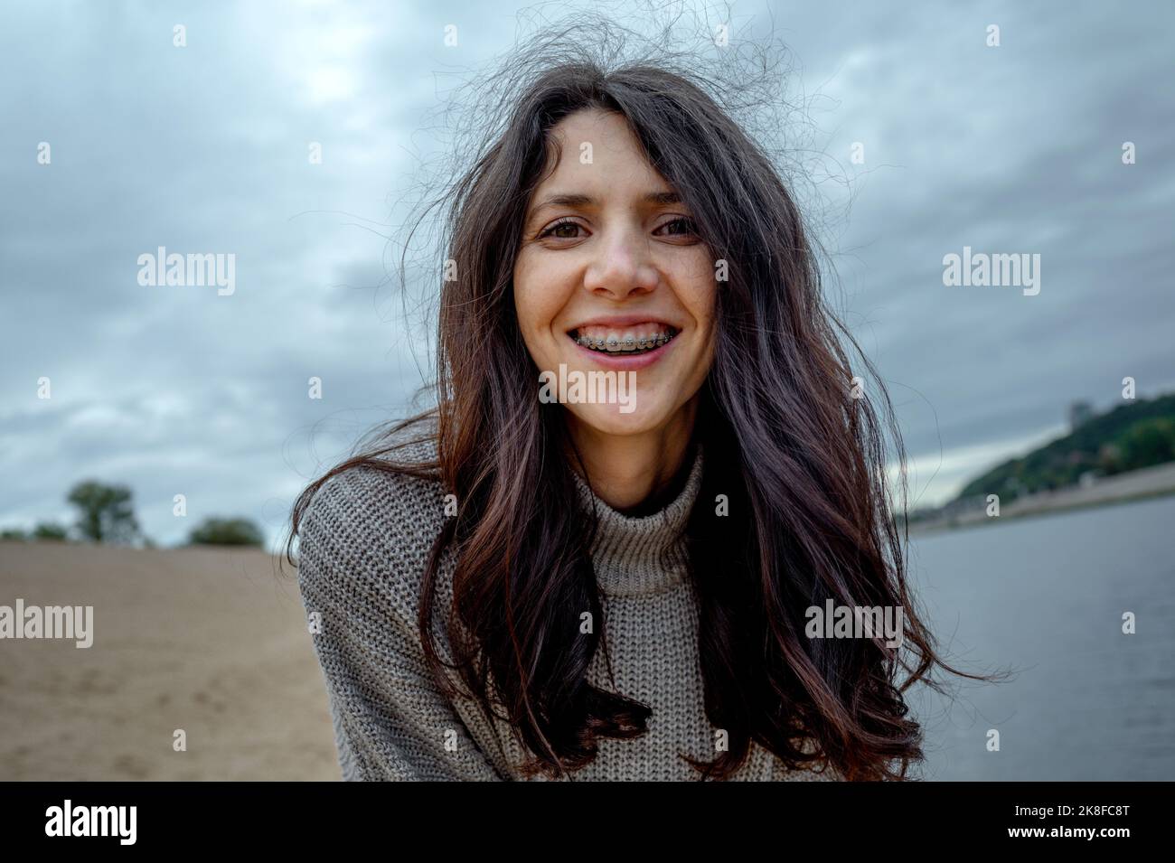 Happy woman with braces standing at riverbank Stock Photo - Alamy