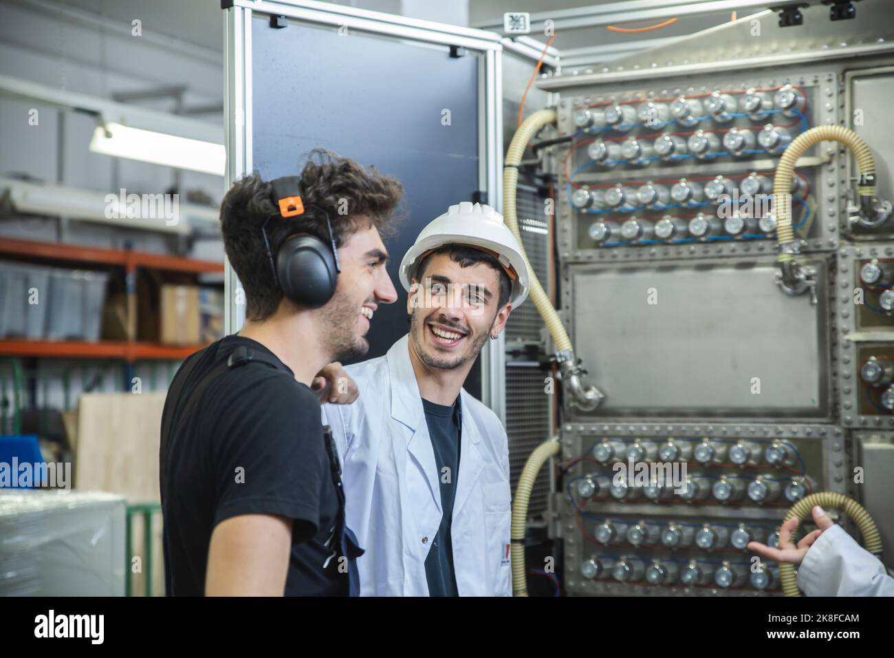 Technician talking with coworkers by production line in factory Stock Photo