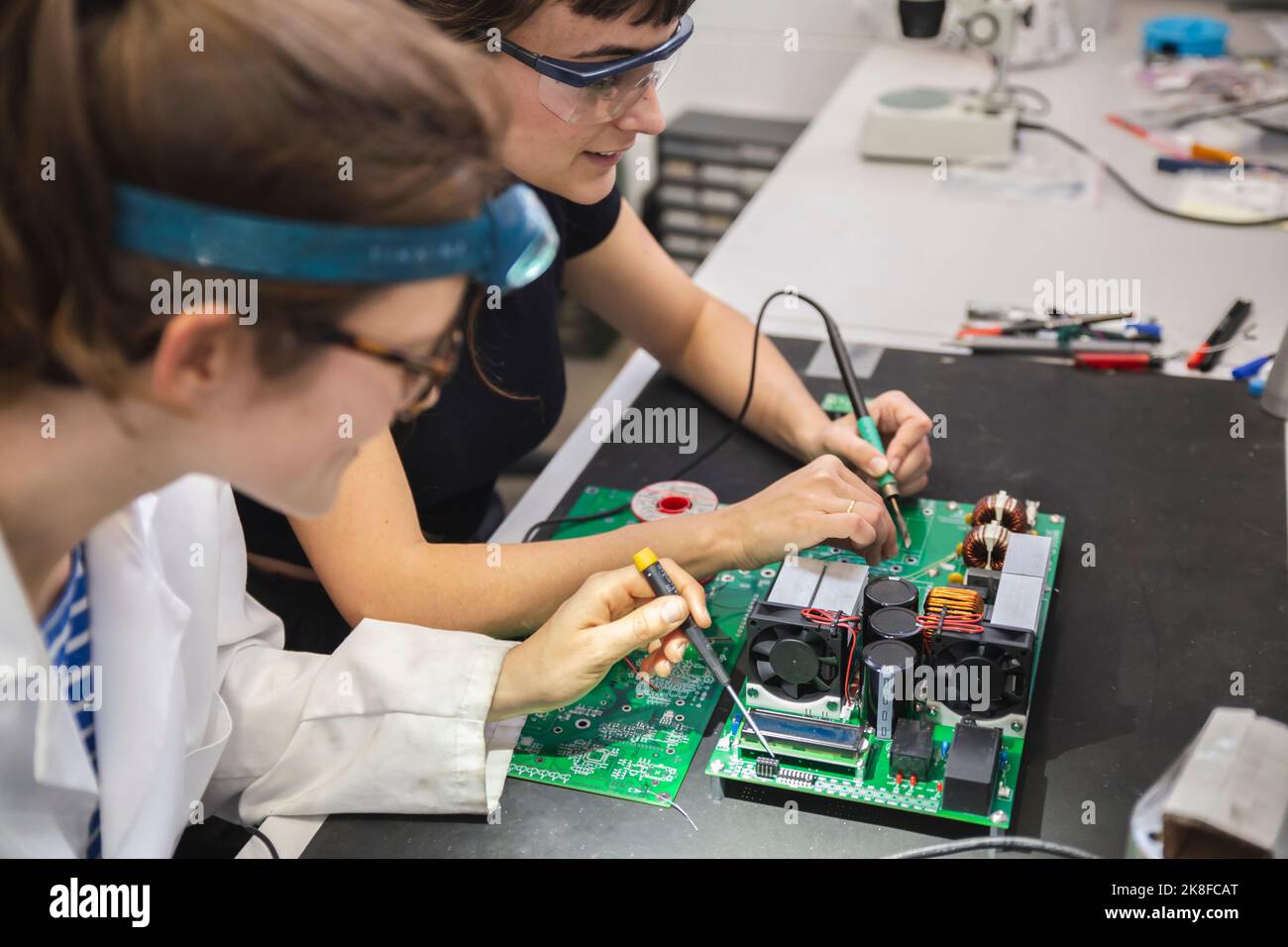 Female technicians soldering motherboard on table in Stock