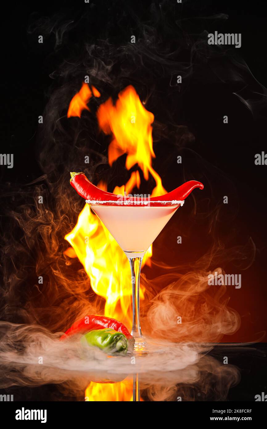Glass of tasty margarita cocktail with chili pepper and fire flame on