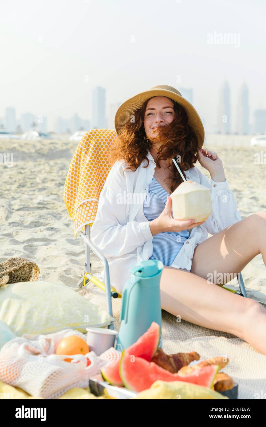 Happy woman with coconut enjoying sunny day at beach Stock Photo