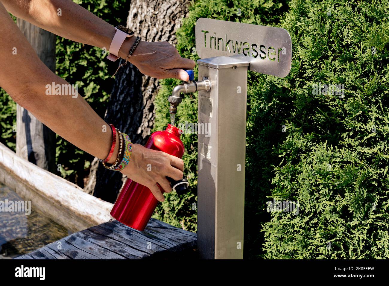 Hands of woman filling water in bottle from drinking fountain Stock