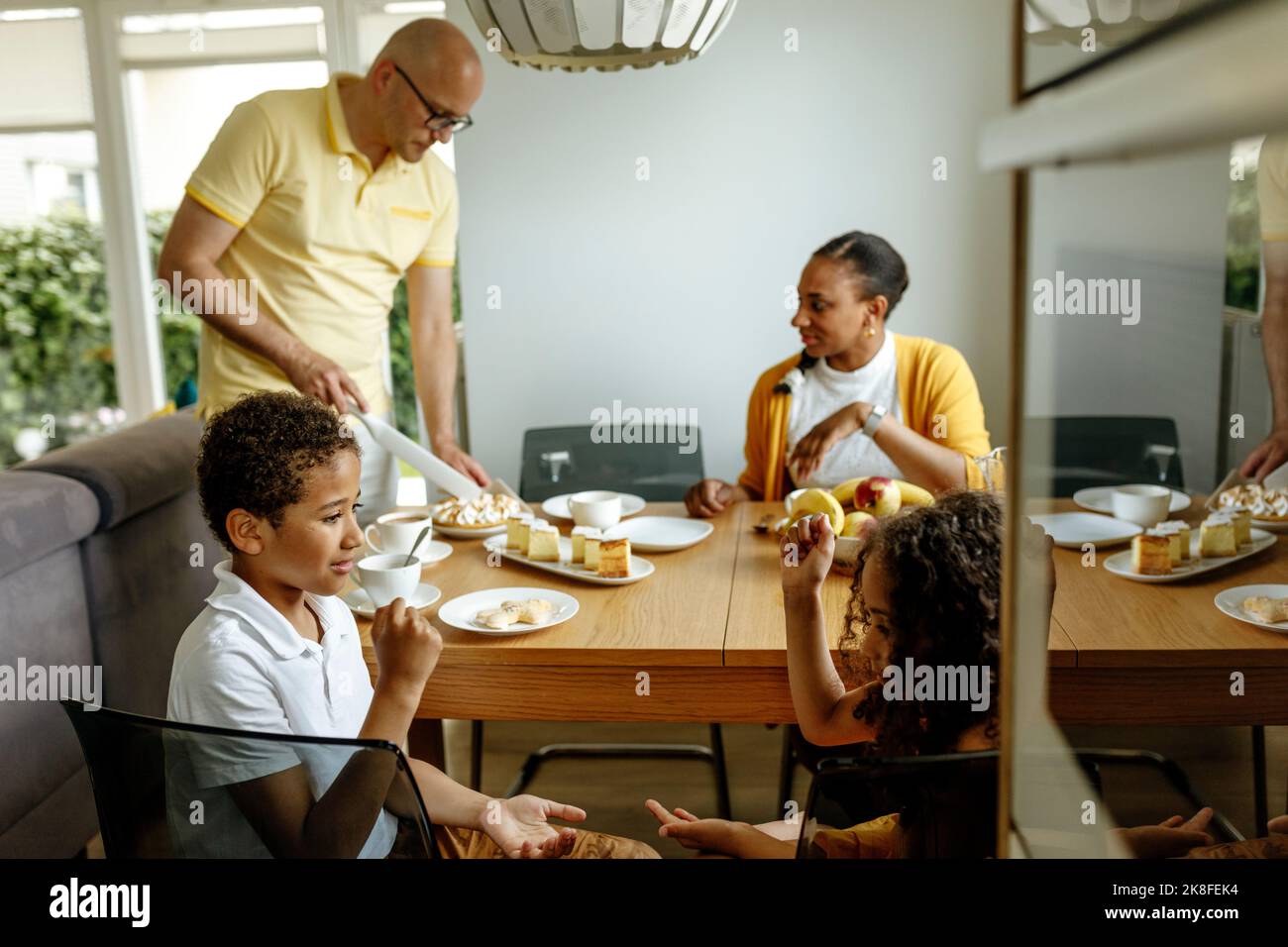 Children playing rock paper scissors game by parents at dining table Stock Photo