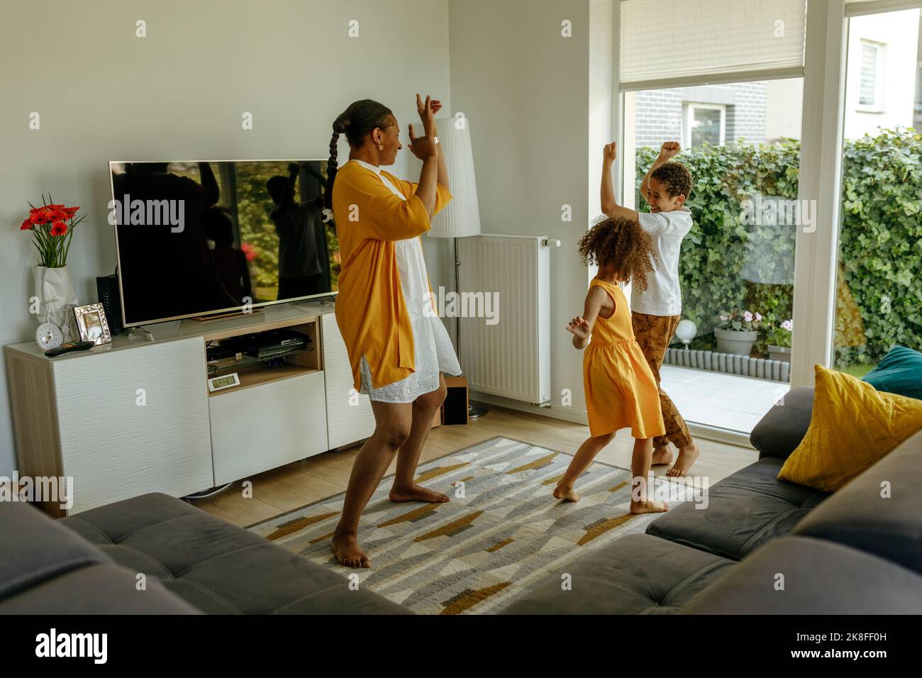 Happy mother with children dancing in living room Stock Photo