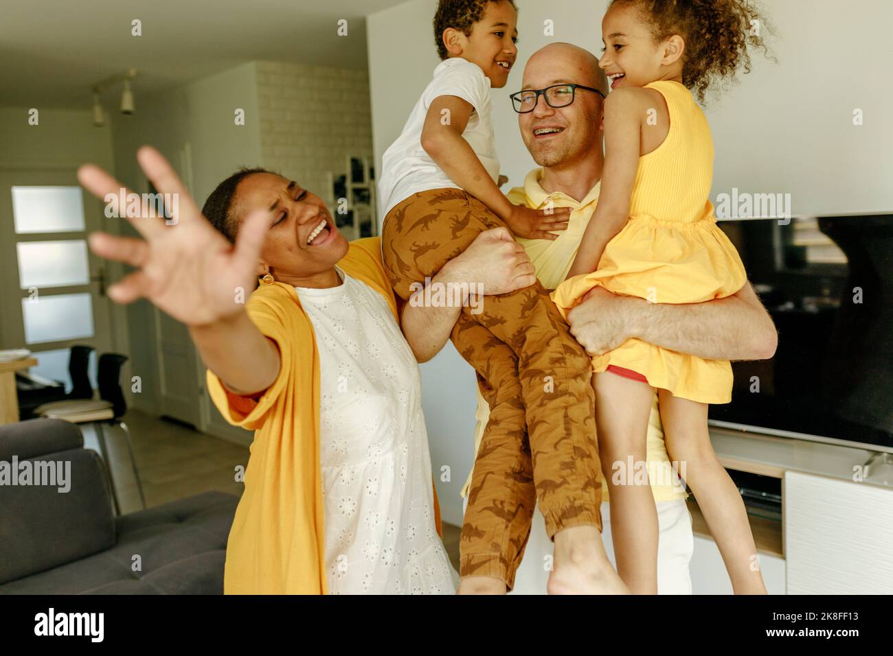 Happy parents with children dancing in living room at home Stock Photo