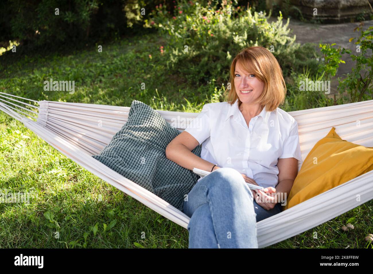 Mature freelancer with tablet PC sitting in hammock Stock Photo