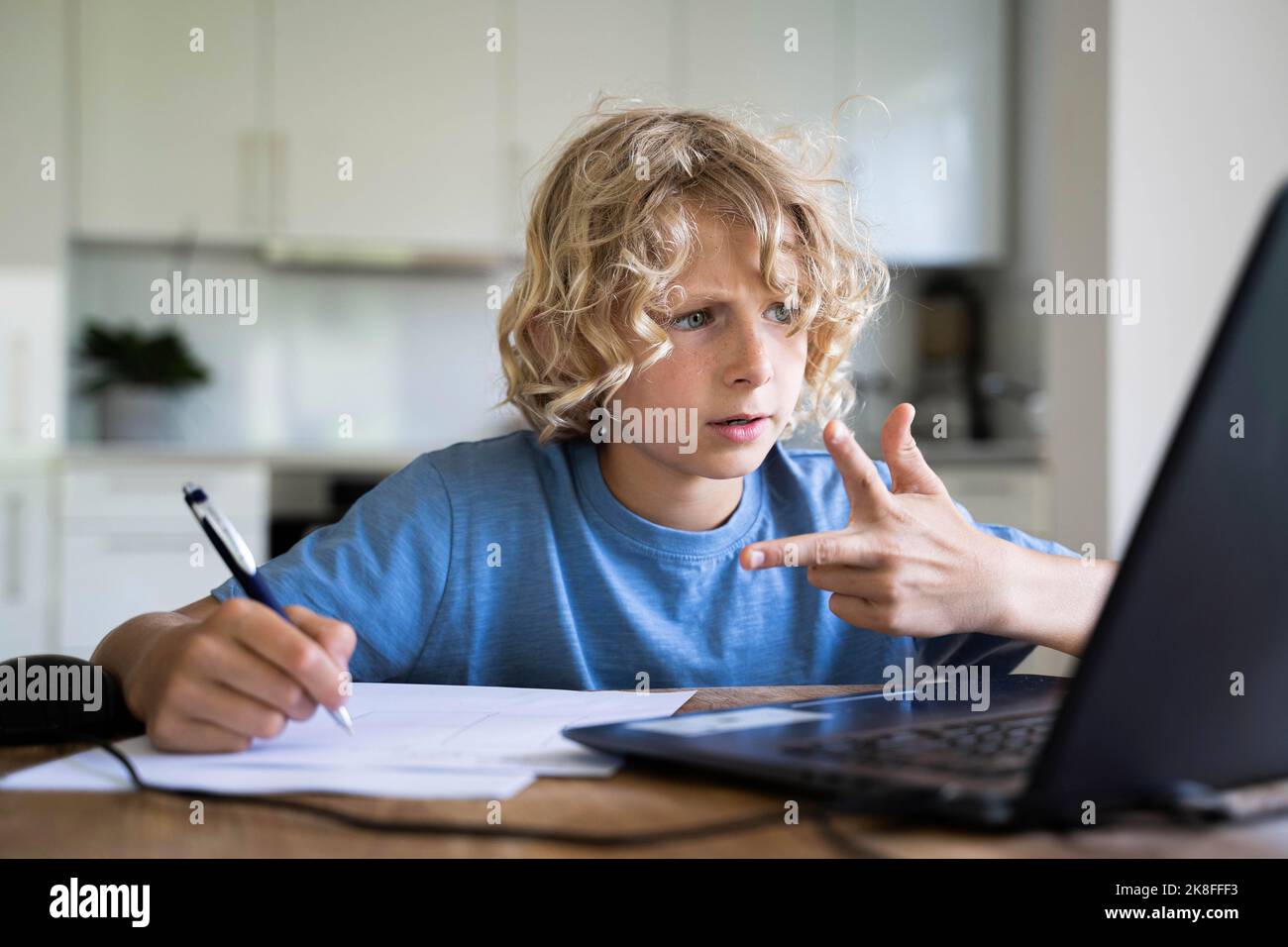 Boy counting through fingers looking at laptop Stock Photo