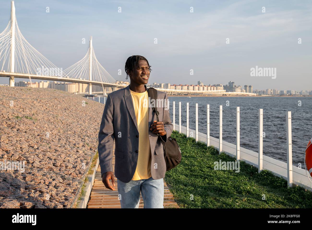 Smiling young businessman with backpack walking on footpath Stock Photo