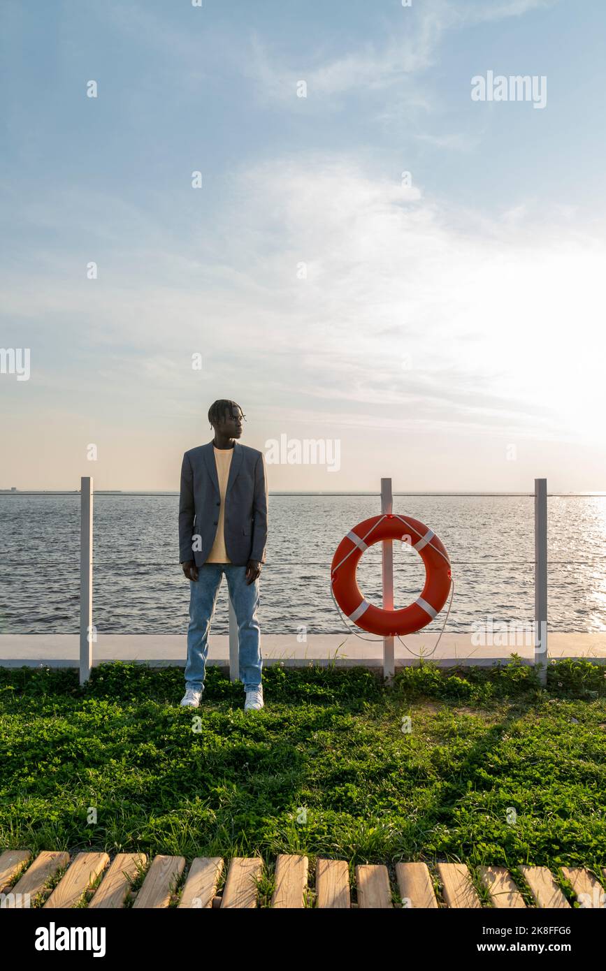 Businessman standing by lifeguard ring on footpath Stock Photo