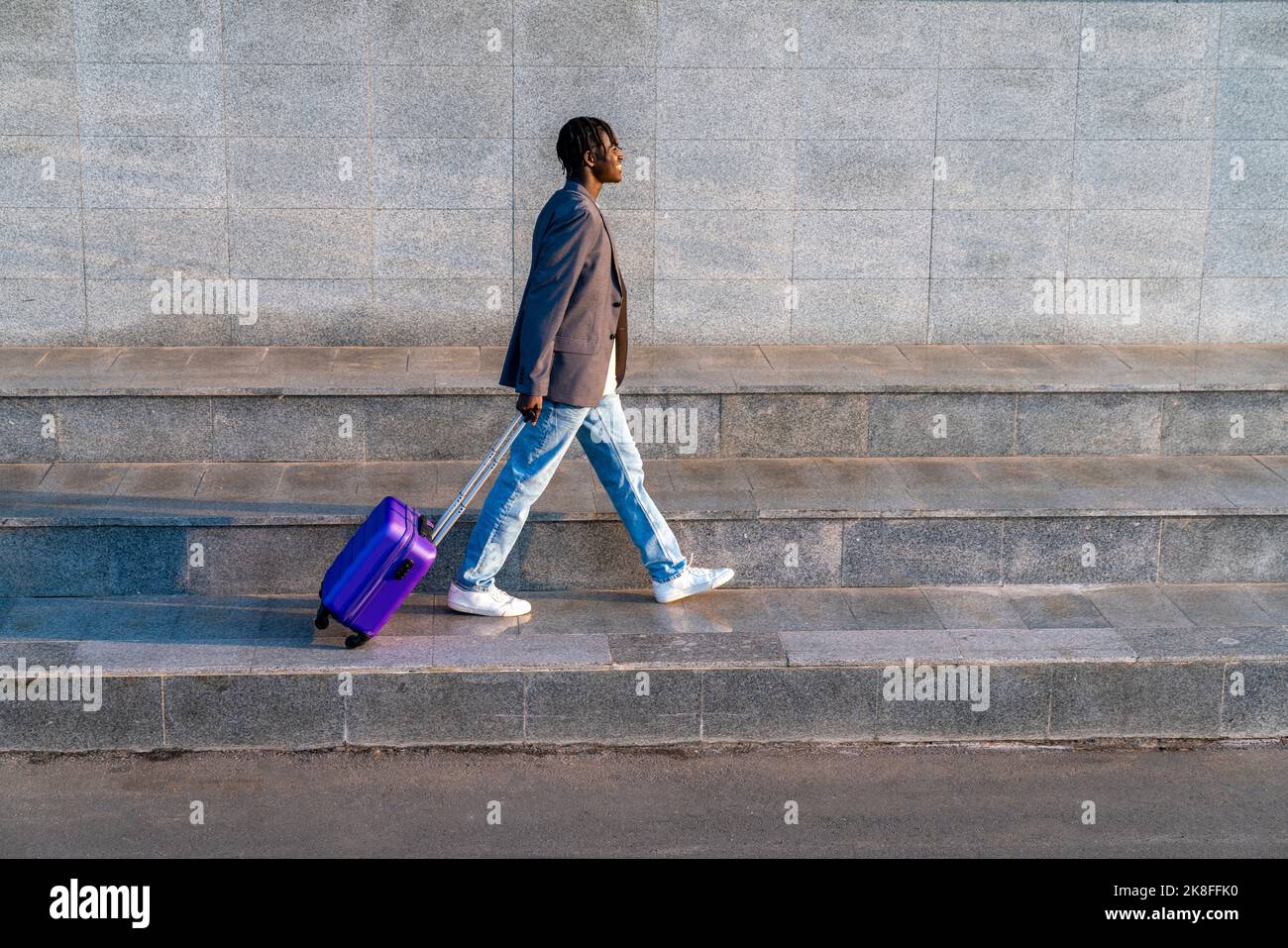Smiling businessman with suitcase walking on step Stock Photo