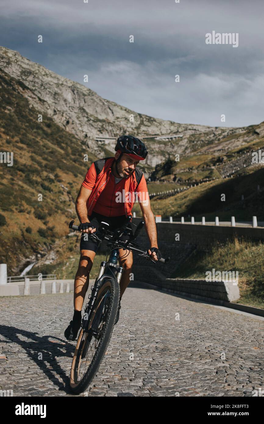 Man cycling on cobbled road at Gotthard Pass Stock Photo