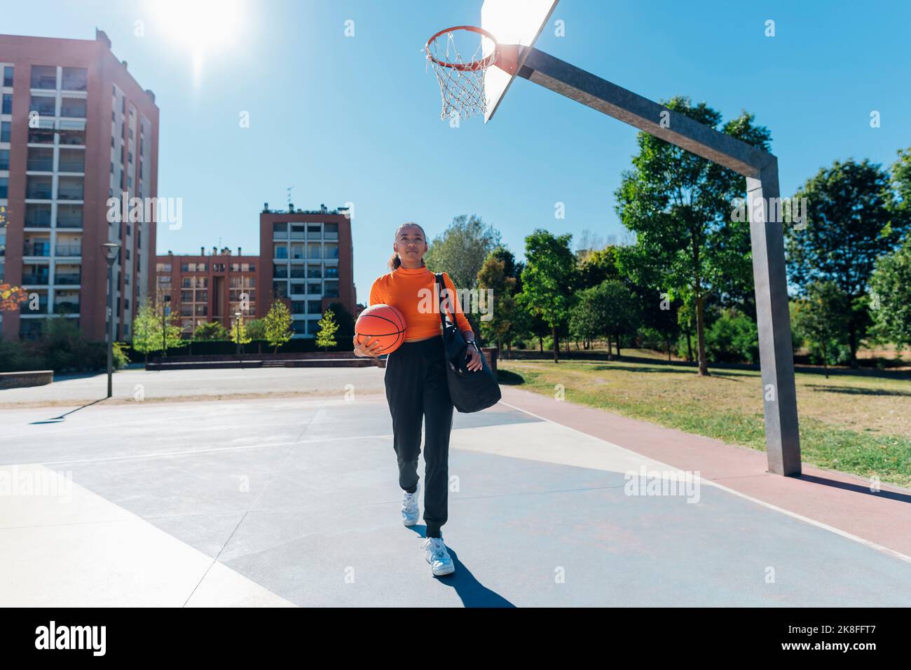 Young sportswoman with basketball walking in sports court Stock Photo ...
