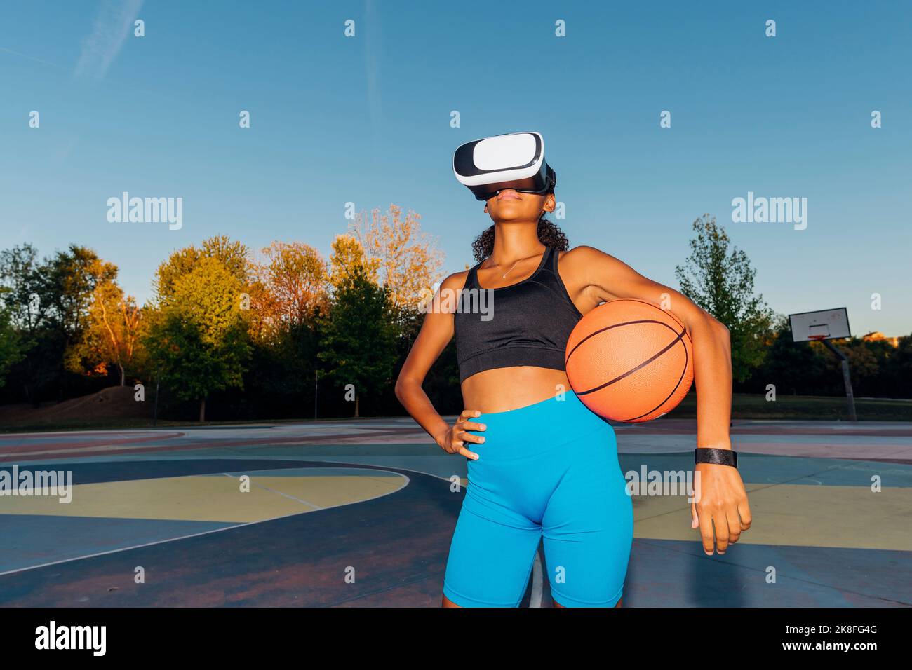 Young basketball player with ball and VR Goggles at sunset Stock Photo